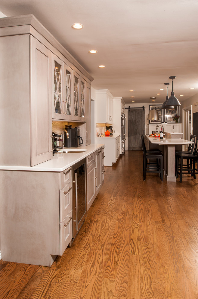 Mid-sized arts and crafts galley light wood floor eat-in kitchen photo in Detroit with an undermount sink, flat-panel cabinets, white cabinets, quartz countertops, white backsplash, ceramic backsplash, stainless steel appliances and an island
