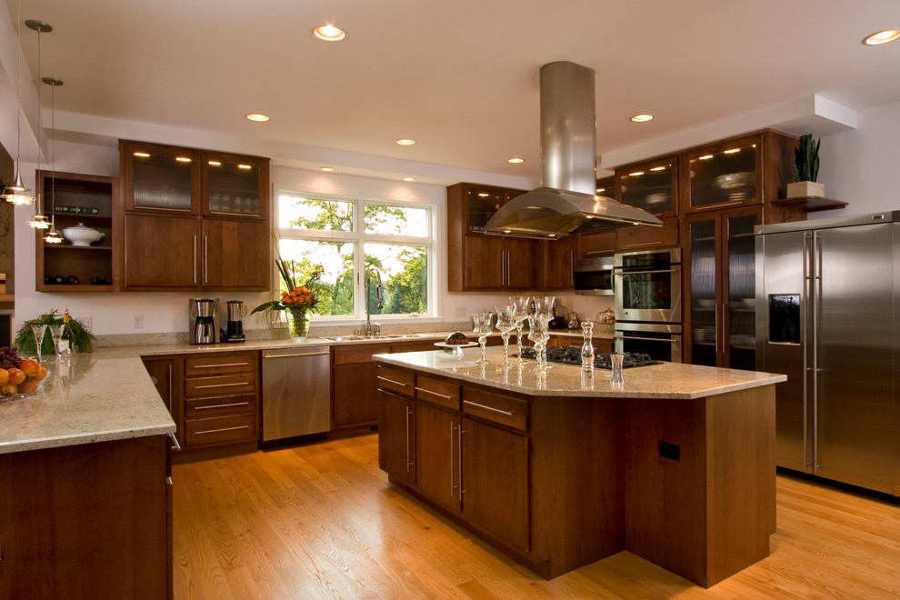 Large classic u-shaped kitchen/diner in Other with a double-bowl sink, flat-panel cabinets, dark wood cabinets, granite worktops, stainless steel appliances, medium hardwood flooring and an island.