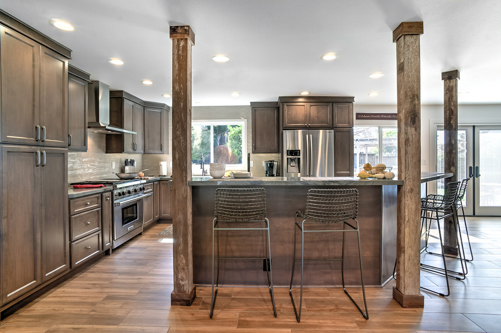 This is an example of a large rustic l-shaped open plan kitchen in San Francisco with a single-bowl sink, raised-panel cabinets, brown cabinets, granite worktops, beige splashback, ceramic splashback, stainless steel appliances, porcelain flooring and an island.
