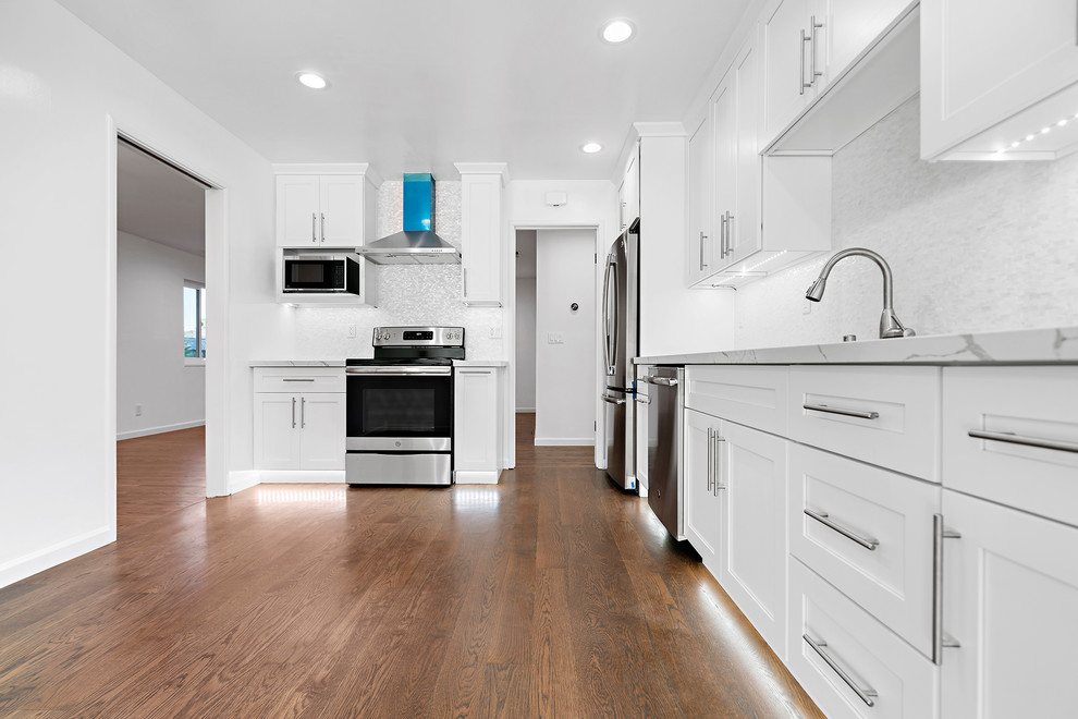 Exempel på ett avskilt, mellanstort modernt vit vitt u-kök, med en undermonterad diskho, skåp i shakerstil, vita skåp, bänkskiva i kvartsit, vitt stänkskydd, rostfria vitvaror, mellanmörkt trägolv och brunt golv