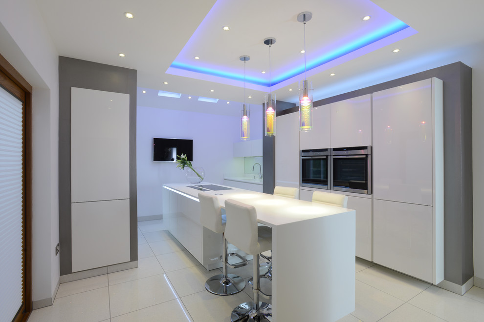 Inspiration for a medium sized contemporary l-shaped enclosed kitchen in Manchester with flat-panel cabinets, white cabinets, stainless steel appliances, an island, composite countertops, blue splashback, glass sheet splashback, porcelain flooring and white floors.