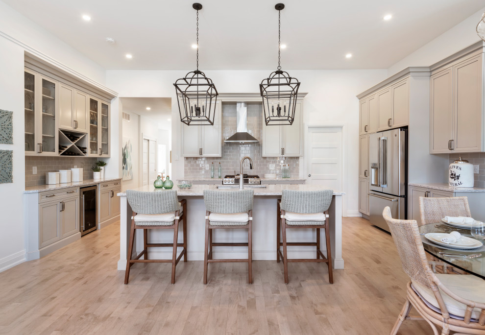 Transitional u-shaped medium tone wood floor and brown floor eat-in kitchen photo in Ottawa with an undermount sink, shaker cabinets, beige cabinets, gray backsplash, subway tile backsplash, stainless steel appliances, an island and multicolored countertops