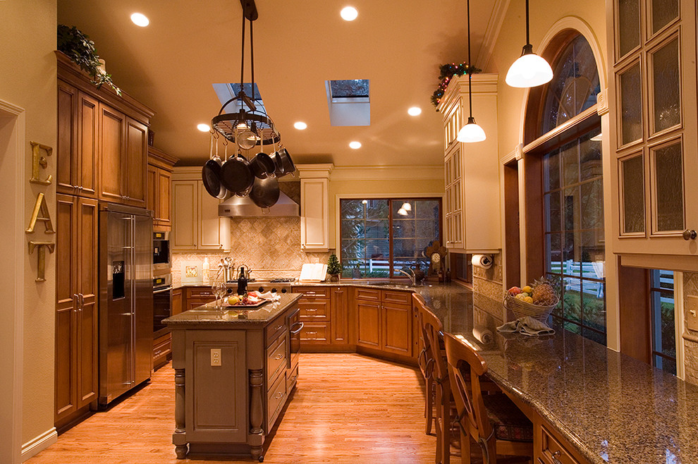 Exempel på ett stort klassiskt kök, med en undermonterad diskho, skåp i shakerstil, skåp i mellenmörkt trä, granitbänkskiva, beige stänkskydd, stänkskydd i keramik, rostfria vitvaror, ljust trägolv och en köksö
