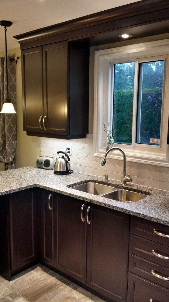 This is an example of a small traditional l-shaped kitchen/diner in Ottawa with a double-bowl sink, recessed-panel cabinets, dark wood cabinets, granite worktops, grey splashback, ceramic splashback, stainless steel appliances, porcelain flooring and a breakfast bar.