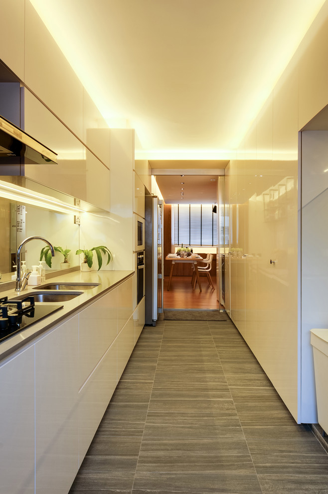 Medium sized contemporary single-wall enclosed kitchen in Singapore with a submerged sink, flat-panel cabinets, white cabinets, quartz worktops, mirror splashback, black appliances, slate flooring and no island.