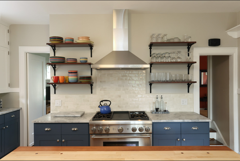 На фото: отдельная кухня в стиле неоклассика (современная классика) с фасадами в стиле шейкер, синими фасадами, бежевым фартуком, фартуком из плитки кабанчик и техникой из нержавеющей стали