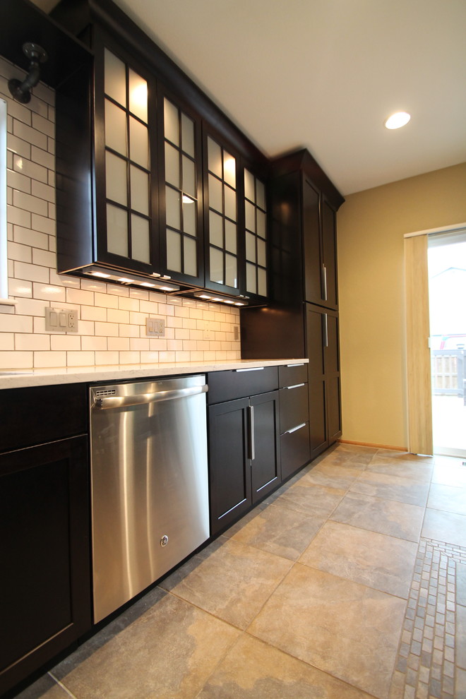 Example of a large urban l-shaped slate floor open concept kitchen design in Denver with an undermount sink, shaker cabinets, dark wood cabinets, quartz countertops, white backsplash, subway tile backsplash, stainless steel appliances and an island