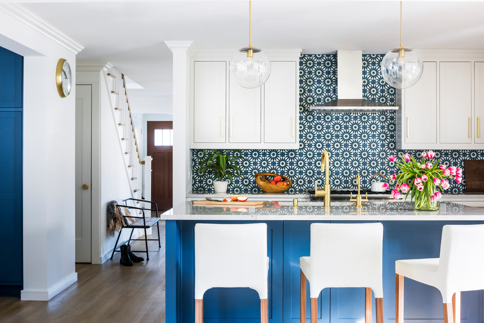 Klassische Küche mit Schrankfronten im Shaker-Stil, weißen Schränken, Küchenrückwand in Blau, braunem Holzboden, Kücheninsel, braunem Boden und weißer Arbeitsplatte in Dallas