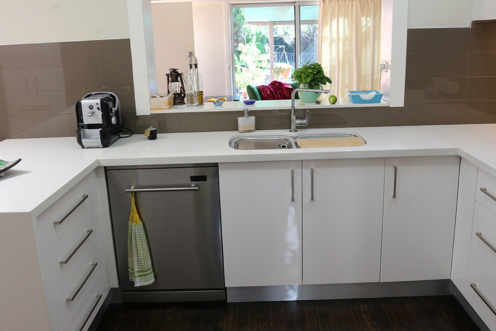 Large modern u-shaped open plan kitchen in Sydney with a submerged sink, flat-panel cabinets, white cabinets, engineered stone countertops, brown splashback, glass sheet splashback, stainless steel appliances, multiple islands and white worktops.