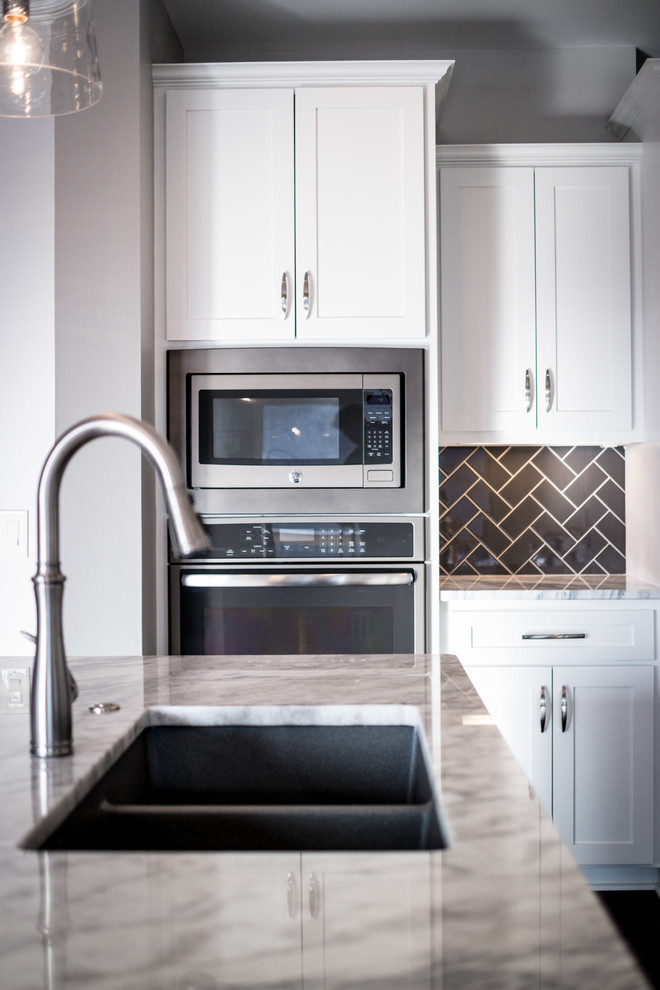 Foto de cocina minimalista de tamaño medio con fregadero bajoencimera, armarios estilo shaker, puertas de armario blancas, encimera de granito, salpicadero verde, salpicadero de azulejos tipo metro, electrodomésticos de acero inoxidable, suelo de madera oscura y una isla