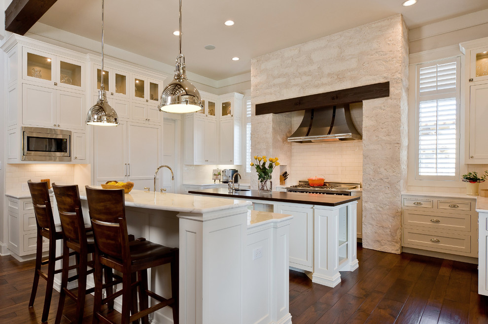 Imagen de cocina clásica con armarios tipo vitrina, electrodomésticos de acero inoxidable, puertas de armario blancas y pared de piedra