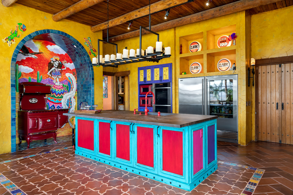 Пример оригинального дизайна: большая п-образная кухня в стиле фьюжн с обеденным столом, врезной мойкой, фасадами в стиле шейкер, красными фасадами, разноцветным фартуком, цветной техникой, полом из терракотовой плитки, островом, черной столешницей, деревянной столешницей, фартуком из цементной плитки и коричневым полом