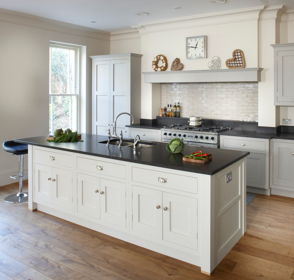 Photo of a classic l-shaped kitchen/diner in London with a double-bowl sink, shaker cabinets, grey cabinets, granite worktops, grey splashback, metro tiled splashback and stainless steel appliances.