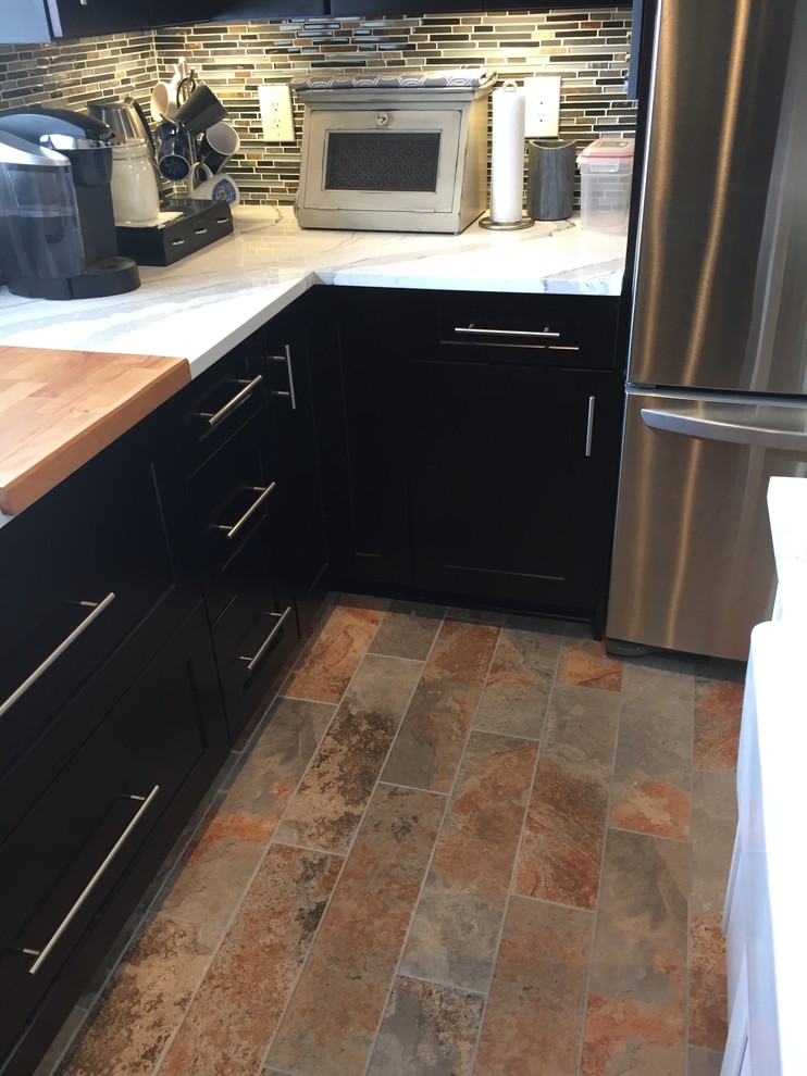 Enclosed kitchen - mid-sized contemporary u-shaped porcelain tile enclosed kitchen idea in New York with a farmhouse sink, shaker cabinets, black cabinets, quartz countertops, multicolored backsplash, mosaic tile backsplash, stainless steel appliances and an island