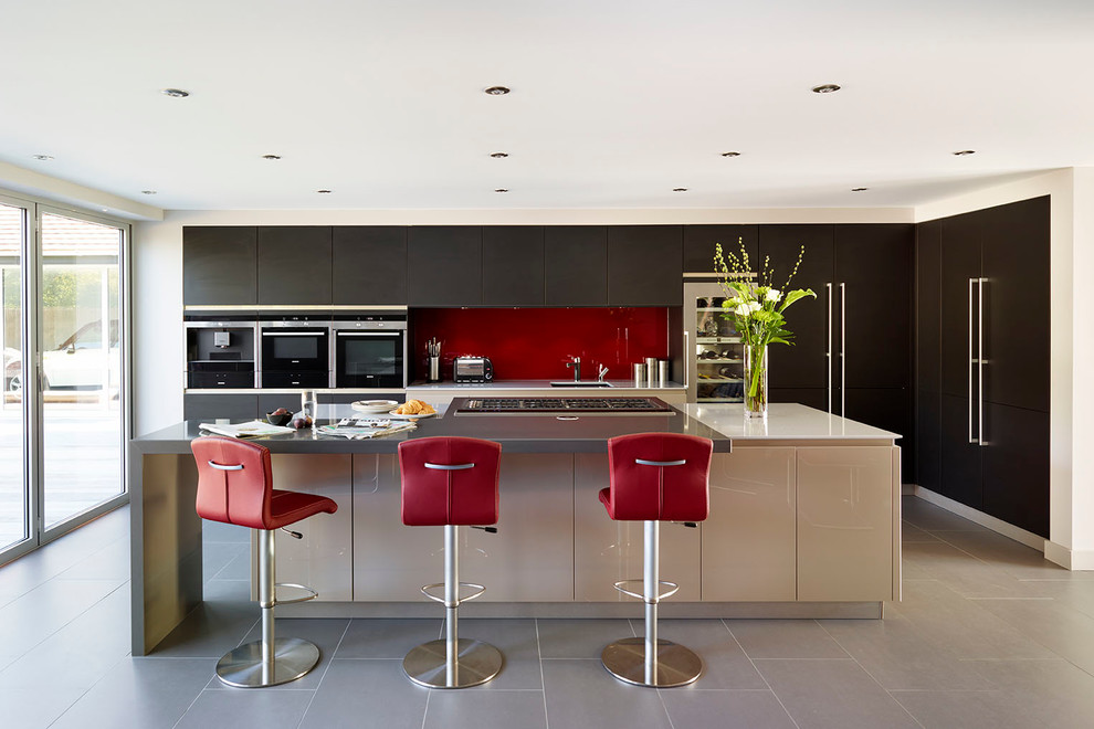 Exempel på ett modernt kök, med en undermonterad diskho, släta luckor, skåp i mörkt trä, rött stänkskydd, glaspanel som stänkskydd, integrerade vitvaror och en köksö