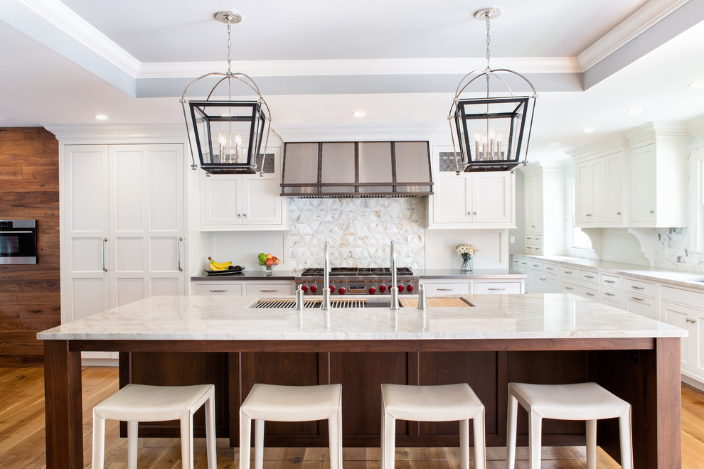 Example of a large beach style medium tone wood floor kitchen design in New York with an undermount sink, white cabinets, quartzite countertops, multicolored backsplash, marble backsplash, stainless steel appliances, an island, beige countertops and shaker cabinets