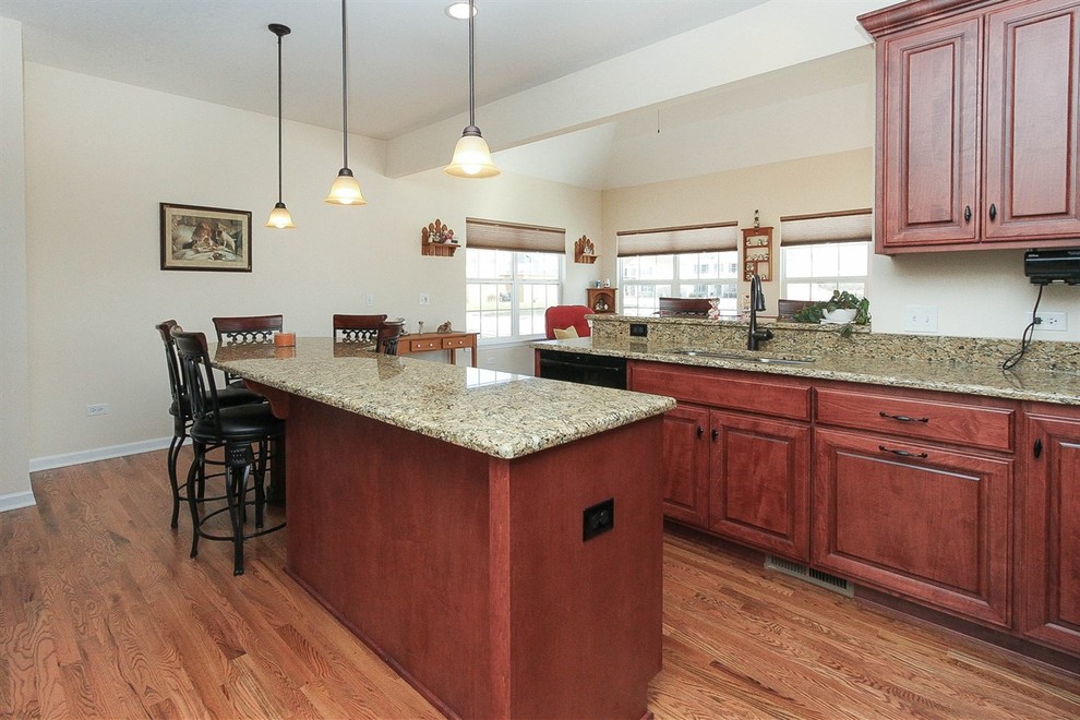 Immagine di una cucina chic di medie dimensioni con lavello sottopiano, ante con bugna sagomata, ante rosse, top in granito, elettrodomestici neri e pavimento in legno massello medio