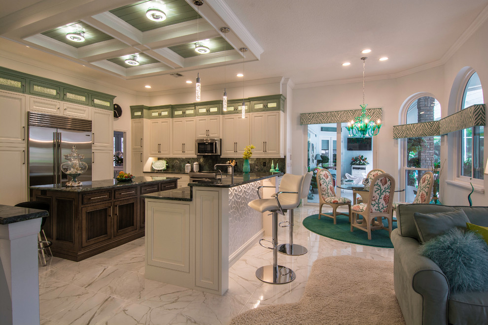 Foto på ett stort tropiskt kök, med en undermonterad diskho, luckor med profilerade fronter, vita skåp, bänkskiva i kvartsit, grönt stänkskydd, stänkskydd i sten, rostfria vitvaror och klinkergolv i porslin