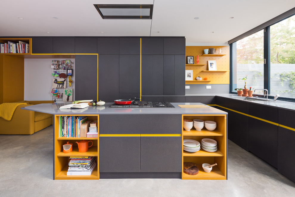 Bild på ett funkis l-kök, med en undermonterad diskho, släta luckor, gula skåp, en köksö och grått golv