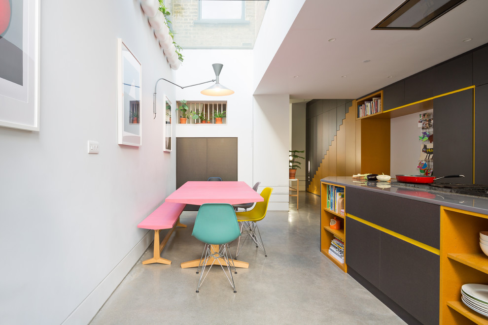 На фото: кухня в современном стиле с обеденным столом, плоскими фасадами, серыми фасадами, бетонным полом и серым полом с