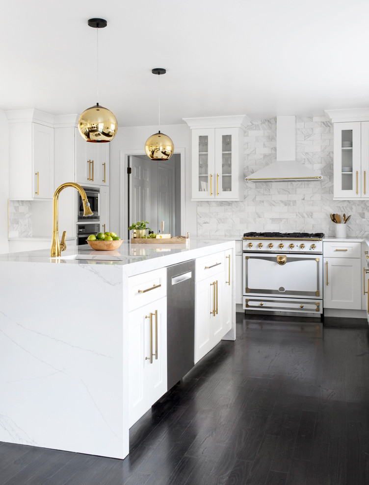 Example of a transitional dark wood floor and black floor kitchen design in New York with an undermount sink, shaker cabinets, white cabinets, white backsplash, marble backsplash, white appliances, an island and white countertops