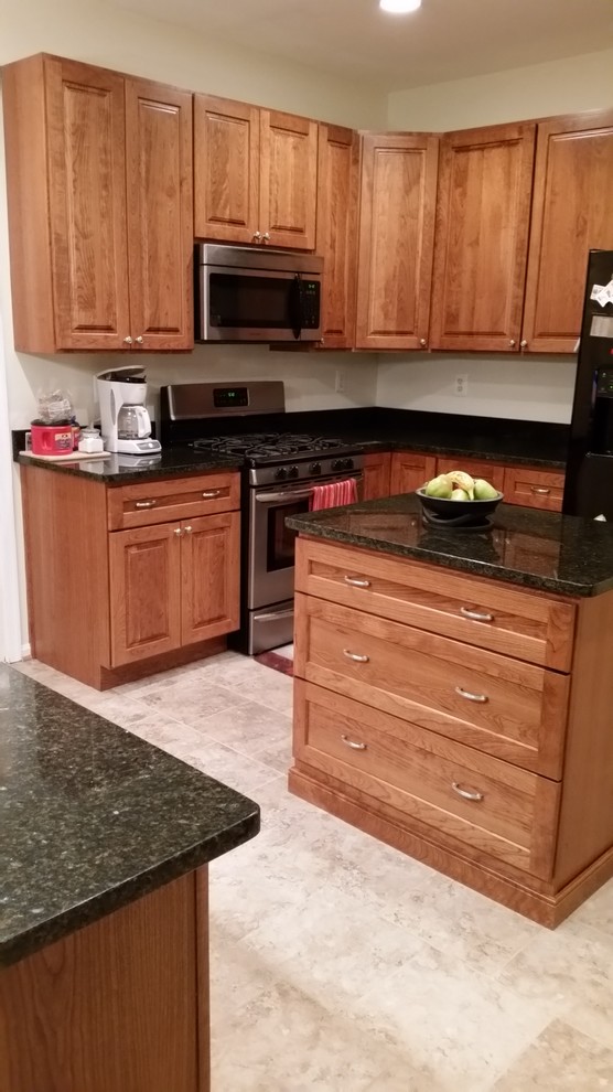 Foto di una cucina classica di medie dimensioni con ante con bugna sagomata, ante in legno scuro, top in granito, elettrodomestici in acciaio inossidabile, pavimento in gres porcellanato e pavimento beige