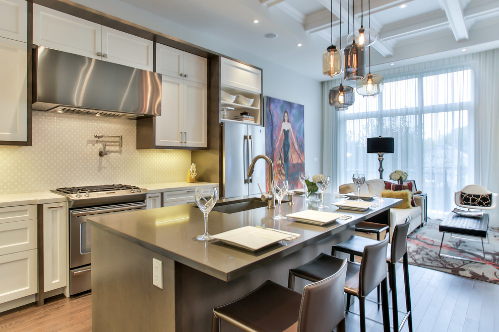 Traditional galley open plan kitchen in Toronto with a submerged sink, shaker cabinets, white cabinets and stainless steel appliances.