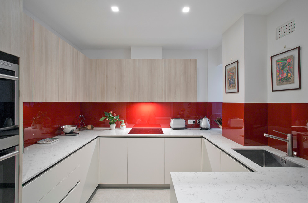 Exempel på ett avskilt, mellanstort modernt u-kök, med skåp i ljust trä, marmorbänkskiva, rött stänkskydd, glaspanel som stänkskydd, rostfria vitvaror, en undermonterad diskho, släta luckor och en halv köksö