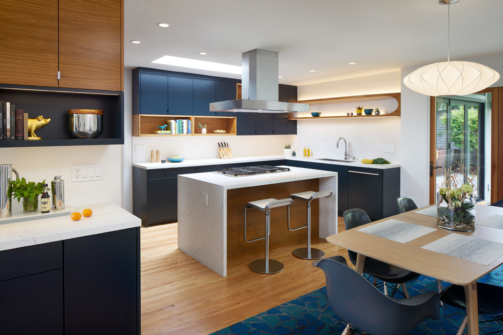 サンフランシスコにある高級な中くらいなミッドセンチュリースタイルのおしゃれなキッチン (フラットパネル扉のキャビネット、青いキャビネット、珪岩カウンター、白いキッチンカウンター、アンダーカウンターシンク、白いキッチンパネル、サブウェイタイルのキッチンパネル、パネルと同色の調理設備、淡色無垢フローリング、ベージュの床) の写真