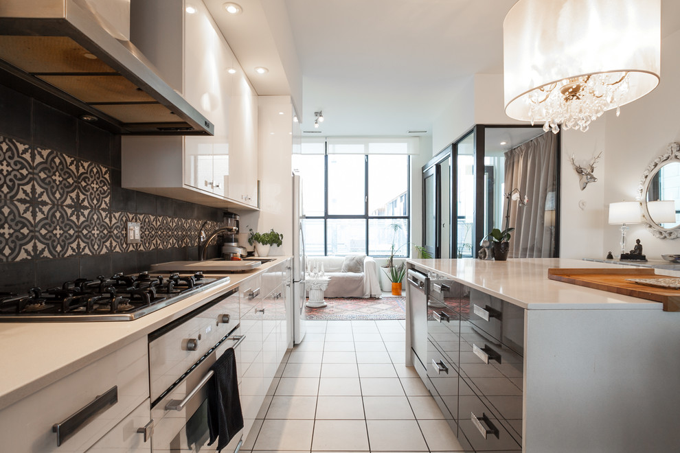Example of a large tuscan ceramic tile open concept kitchen design in Montreal with an undermount sink, flat-panel cabinets, white cabinets, quartz countertops, black backsplash, cement tile backsplash, white appliances and an island
