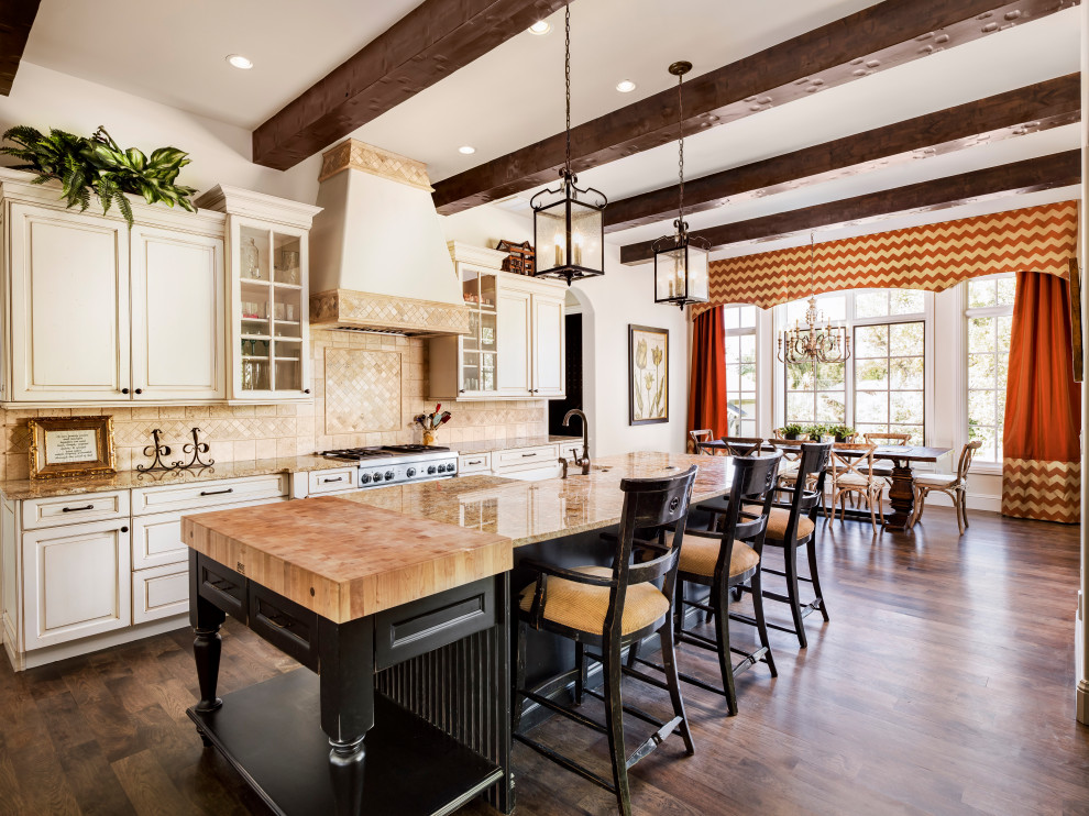 Inspiration for a mediterranean galley dark wood floor and brown floor eat-in kitchen remodel in Denver with a farmhouse sink, raised-panel cabinets, beige cabinets, beige backsplash, stainless steel appliances, an island and beige countertops