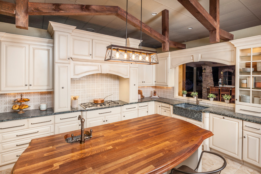 Immagine di una cucina mediterranea con lavello stile country, ante con bugna sagomata, ante beige, paraspruzzi multicolore, pavimento beige e top grigio