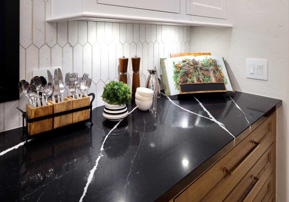 Bild på ett avskilt, stort lantligt svart svart l-kök, med en undermonterad diskho, vita skåp, bänkskiva i kvarts, vitt stänkskydd, stänkskydd i porslinskakel, integrerade vitvaror, marmorgolv och en köksö