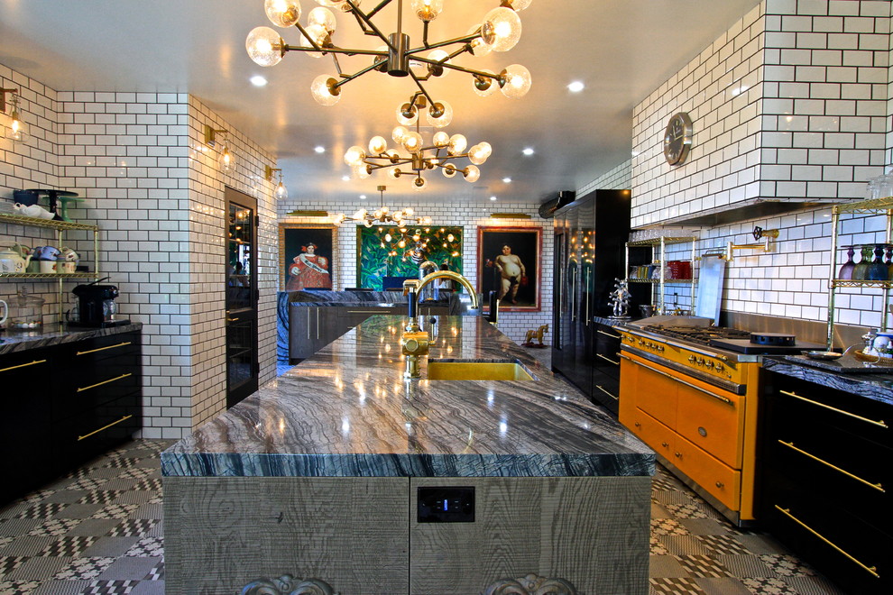 Photo of an expansive eclectic l-shaped enclosed kitchen in Orange County with a submerged sink, flat-panel cabinets, grey cabinets, marble worktops, white splashback, metro tiled splashback, black appliances, ceramic flooring and an island.