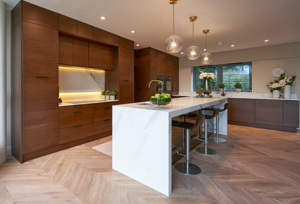 This is an example of a large contemporary l-shaped open plan kitchen in Other with a double-bowl sink, flat-panel cabinets, brown cabinets, quartz worktops, white splashback, ceramic splashback, black appliances, light hardwood flooring, an island, beige floors and white worktops.