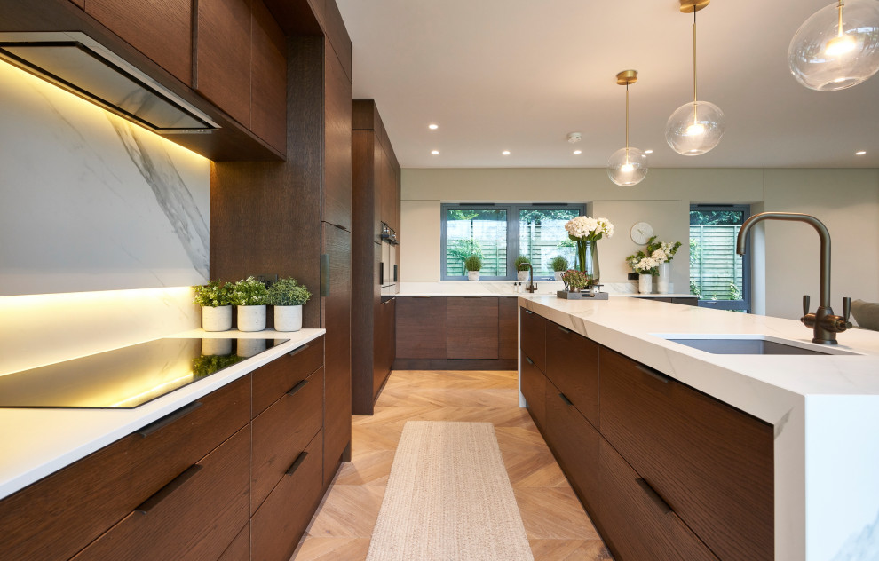 Example of a large minimalist l-shaped light wood floor and beige floor open concept kitchen design in Other with a double-bowl sink, flat-panel cabinets, brown cabinets, quartzite countertops, white backsplash, ceramic backsplash, black appliances, an island and white countertops
