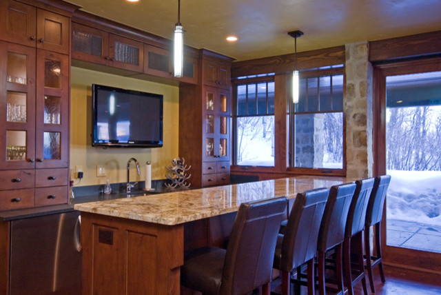 Cette photo montre une grande cuisine ouverte linéaire montagne en bois brun avec un évier intégré, un placard à porte vitrée, un plan de travail en granite, une crédence jaune, un électroménager en acier inoxydable et îlot.