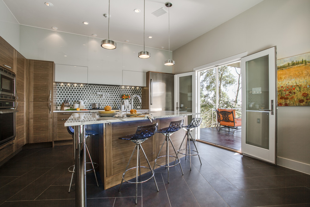 Mid-sized trendy l-shaped porcelain tile and brown floor eat-in kitchen photo in Houston with medium tone wood cabinets, glass tile backsplash, stainless steel appliances, an island, flat-panel cabinets, a double-bowl sink, quartz countertops, gray backsplash and white countertops