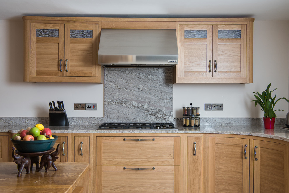 Foto di una cucina abitabile chic di medie dimensioni con lavello sottopiano, top in granito, elettrodomestici neri e pavimento in pietra calcarea