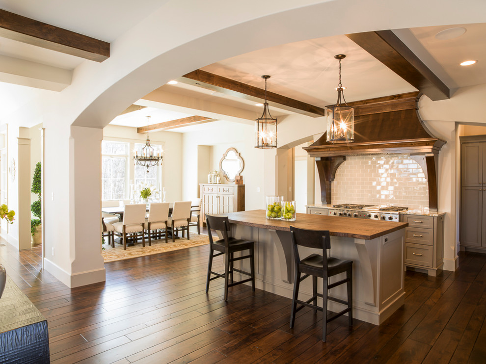 This is an example of a large rustic l-shaped open plan kitchen in Minneapolis with a double-bowl sink, flat-panel cabinets, grey cabinets, wood worktops, grey splashback, metro tiled splashback, stainless steel appliances, medium hardwood flooring and an island.