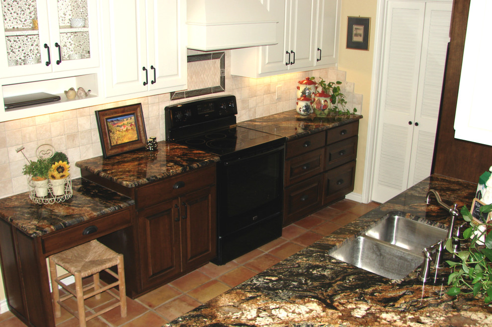 Foto di una grande cucina eclettica con lavello sottopiano, ante di vetro, ante bianche, top in granito, paraspruzzi beige, paraspruzzi con piastrelle in pietra, elettrodomestici neri e pavimento in terracotta