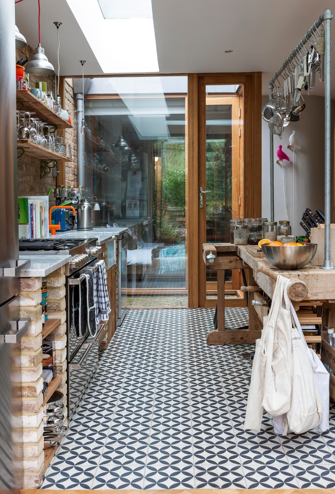 Mid-sized eclectic single-wall cement tile floor and multicolored floor open concept kitchen photo in London with a farmhouse sink, open cabinets, marble countertops and stainless steel appliances