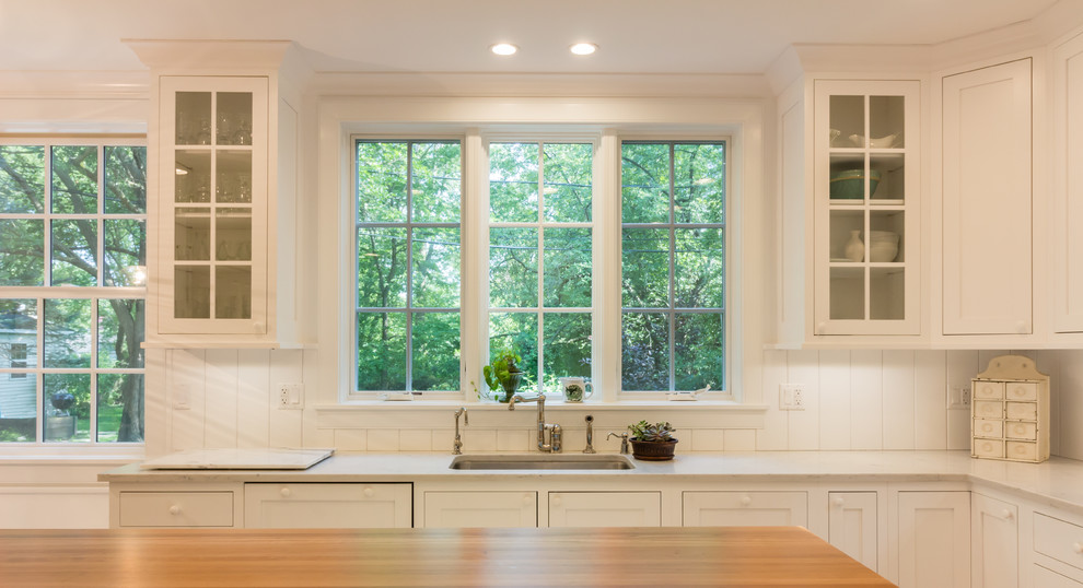 Foto di una cucina chic chiusa con lavello sottopiano, ante di vetro, ante bianche, paraspruzzi bianco, paraspruzzi in legno, elettrodomestici bianchi, pavimento in legno massello medio e pavimento marrone