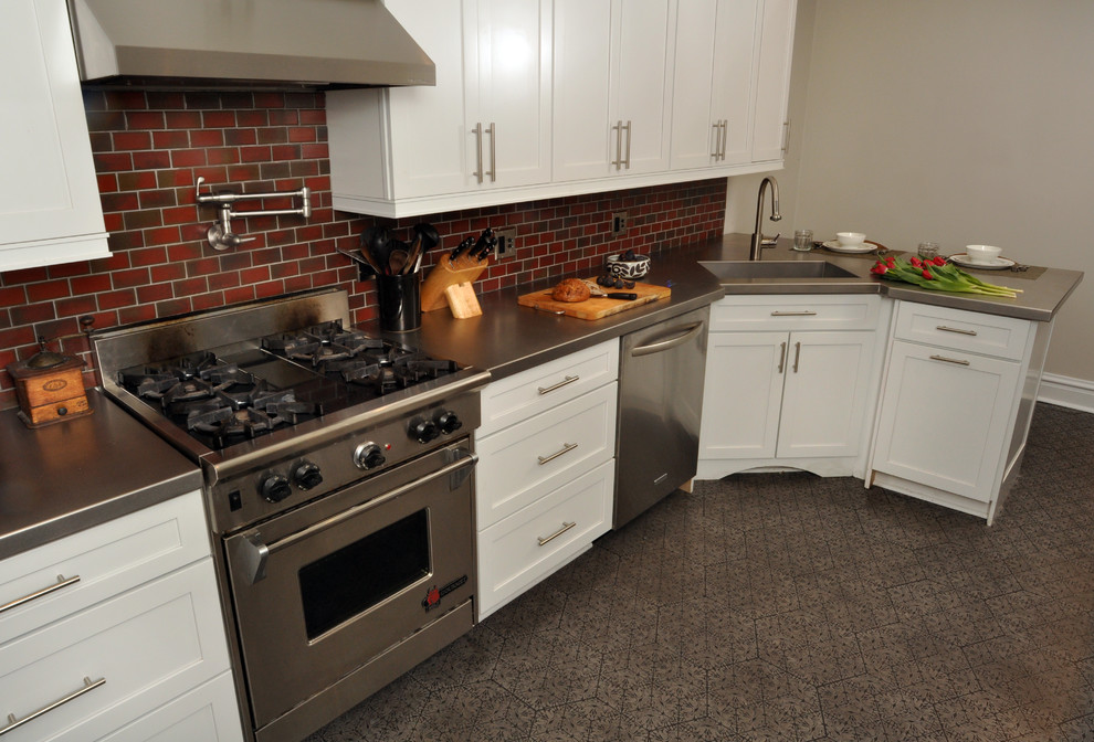 シカゴにある高級な中くらいなコンテンポラリースタイルのおしゃれなキッチン (シルバーの調理設備、ステンレスカウンター、一体型シンク、シェーカースタイル扉のキャビネット、白いキャビネット、赤いキッチンパネル、サブウェイタイルのキッチンパネル) の写真