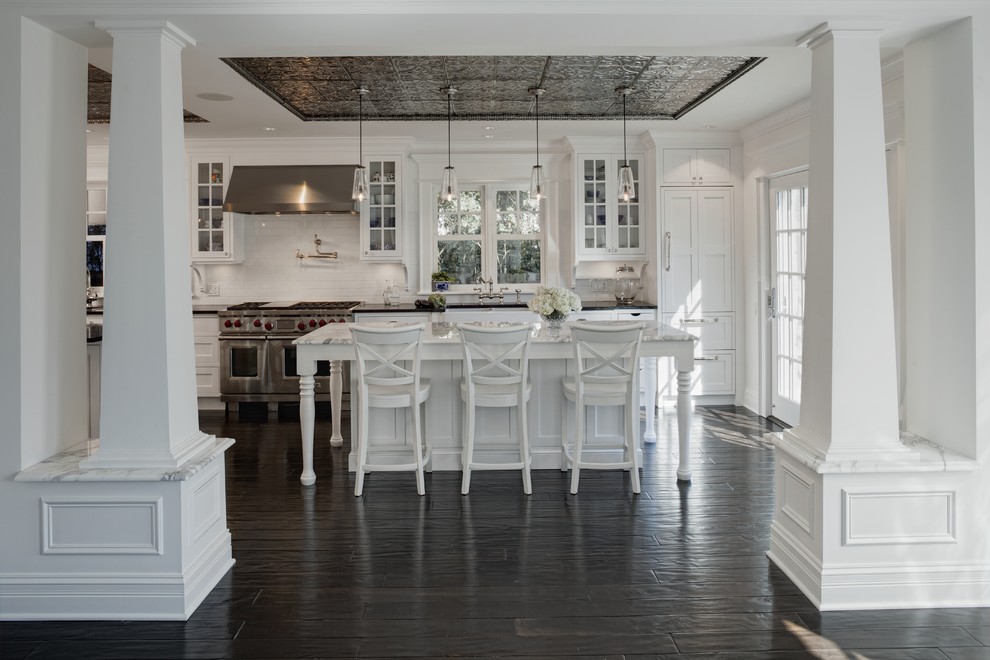 Elegant kitchen photo in Chicago with stainless steel appliances, glass-front cabinets, white cabinets, white backsplash and subway tile backsplash