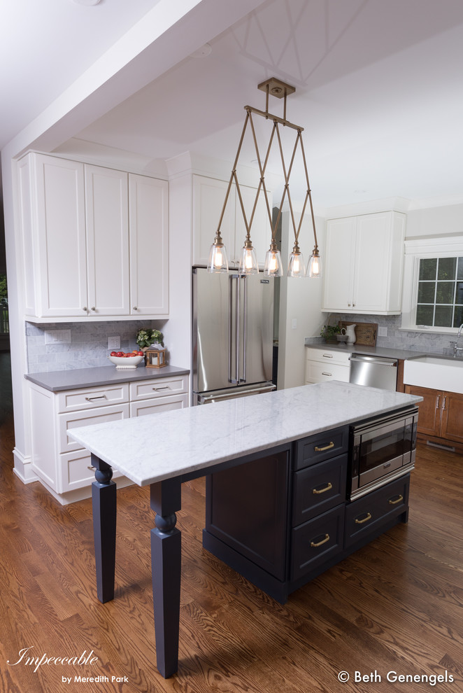 Inspiration for a large classic u-shaped open plan kitchen in Chicago with a belfast sink, flat-panel cabinets, white cabinets, engineered stone countertops, grey splashback, marble splashback, stainless steel appliances, medium hardwood flooring, an island and brown floors.