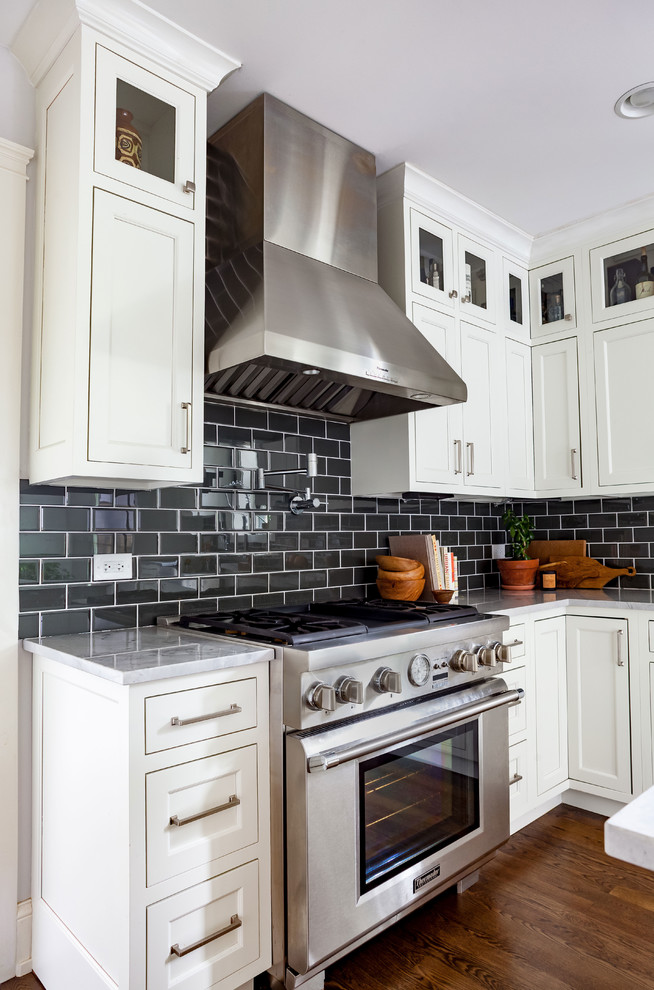 Bild på ett eklektiskt vit vitt kök, med en undermonterad diskho, skåp i shakerstil, vita skåp, granitbänkskiva, svart stänkskydd, stänkskydd i keramik, rostfria vitvaror, mörkt trägolv, en köksö och brunt golv