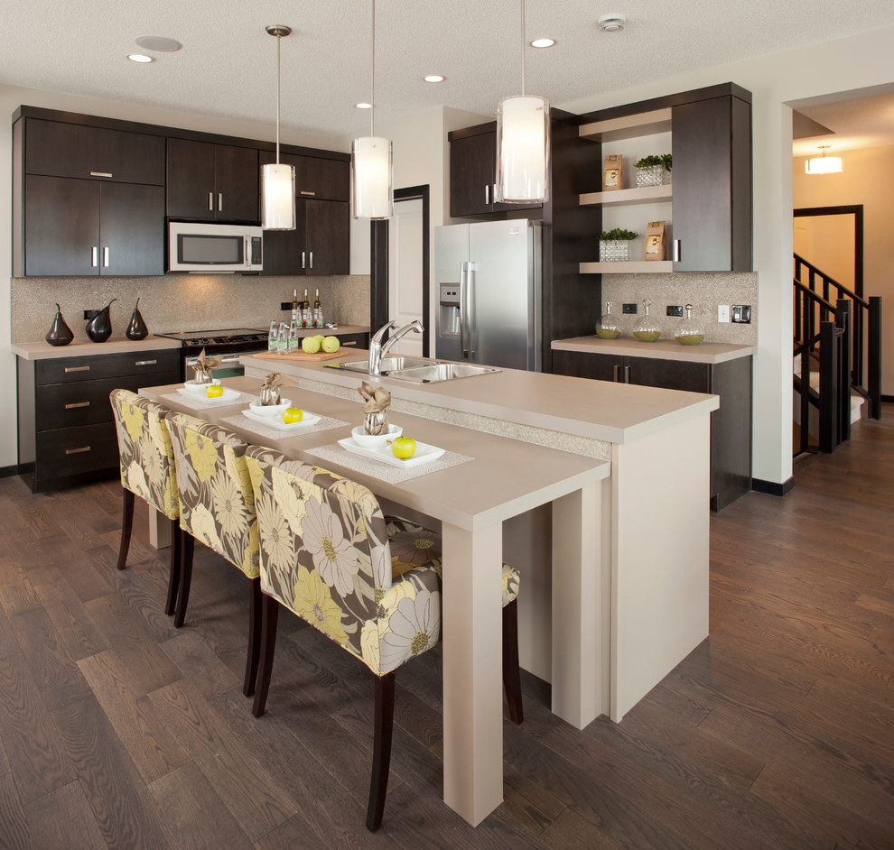 Trendy l-shaped kitchen photo in Calgary with a double-bowl sink, flat-panel cabinets, dark wood cabinets, beige backsplash and stainless steel appliances