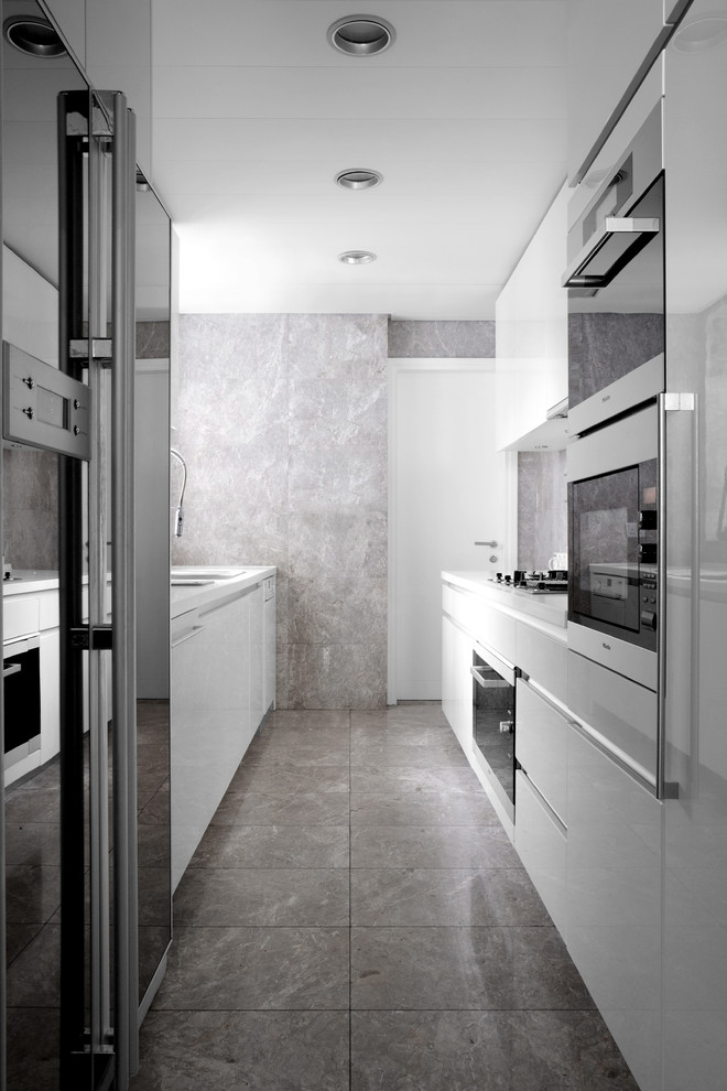 Cette photo montre une petite cuisine parallèle tendance fermée avec un placard à porte plane, des portes de placard blanches, un électroménager noir, aucun îlot et un sol gris.