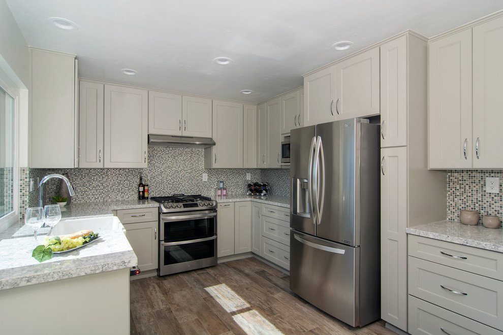 Example of a mid-sized transitional u-shaped porcelain tile and gray floor eat-in kitchen design in San Diego with a farmhouse sink, shaker cabinets, gray cabinets, quartz countertops, multicolored backsplash, mosaic tile backsplash, stainless steel appliances, no island and multicolored countertops